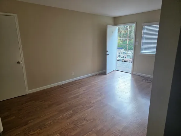 a view of an empty room with wooden floor and a window