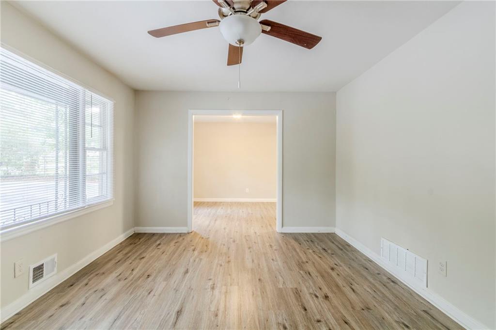 6281 Denny Lane Southwest Mableton, GA 30126 - Photo 9 of 27 an empty room with wooden floor chandelier fan and windows