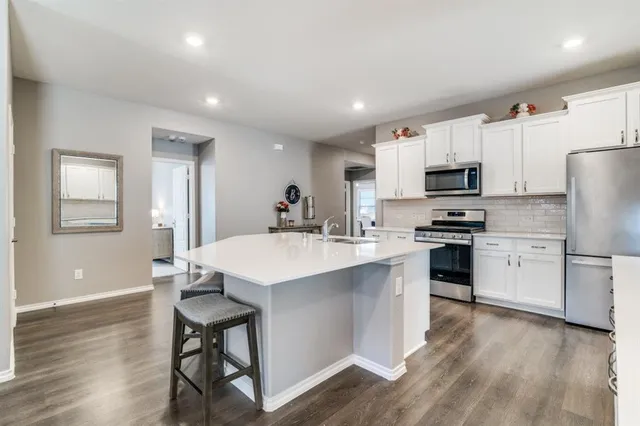 a kitchen with a sink a microwave a refrigerator and white cabinets