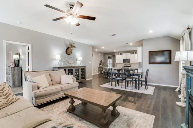 a living room with furniture kitchen view and a wooden floor