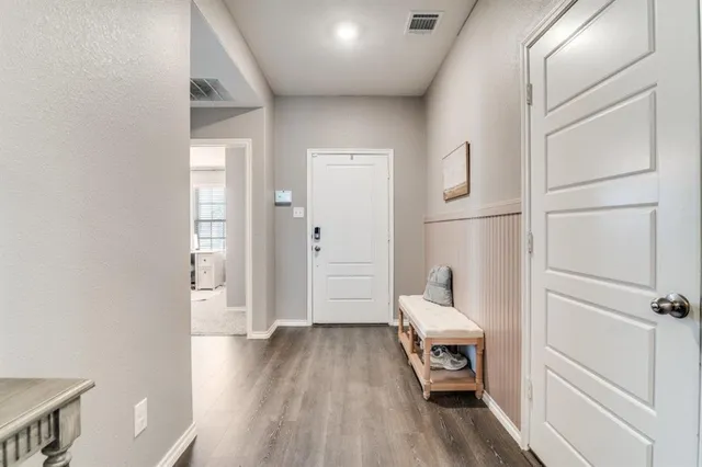 a hallway with wooden floor white cabinet and stairs