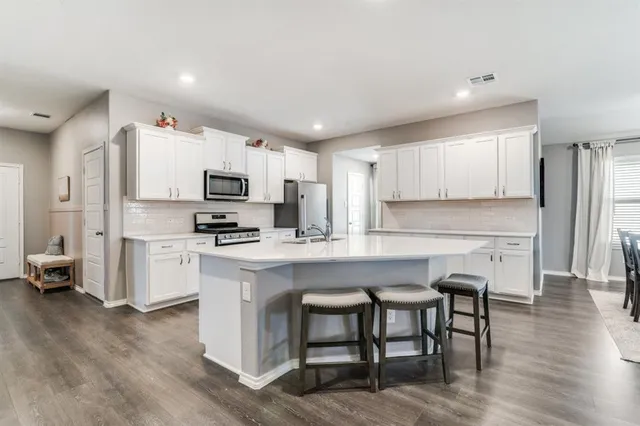 a kitchen with a table chairs refrigerator and microwave