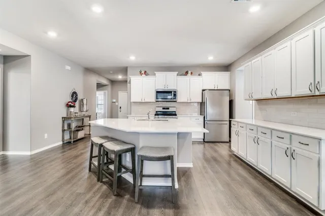 a kitchen with stainless steel appliances granite countertop a table chairs sink refrigerator and cabinets