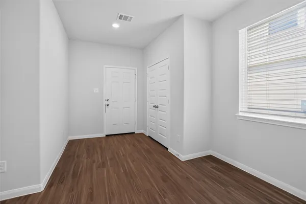 an empty room with wooden floor and windows