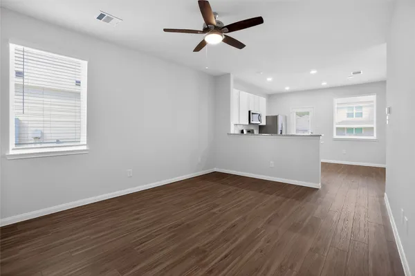 a view of a kitchen with wooden floor a ceiling fan and windows