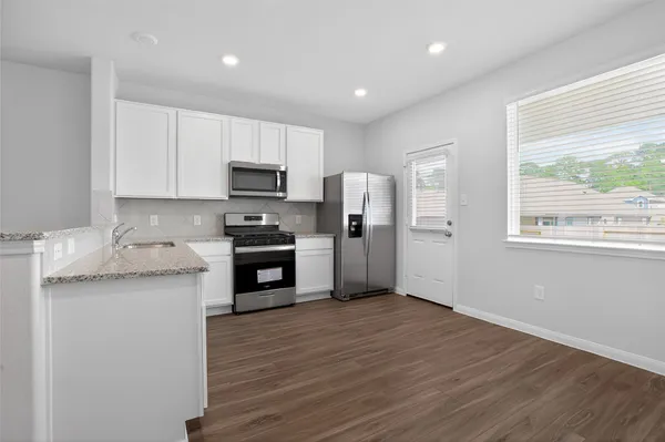 a kitchen with granite countertop a refrigerator and a stove top oven