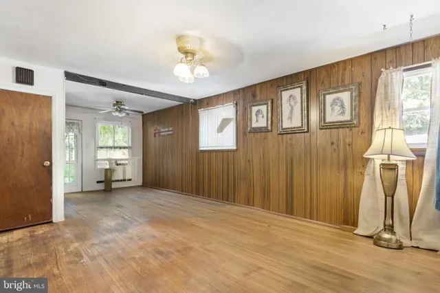 a view of empty room with wooden floor and fan