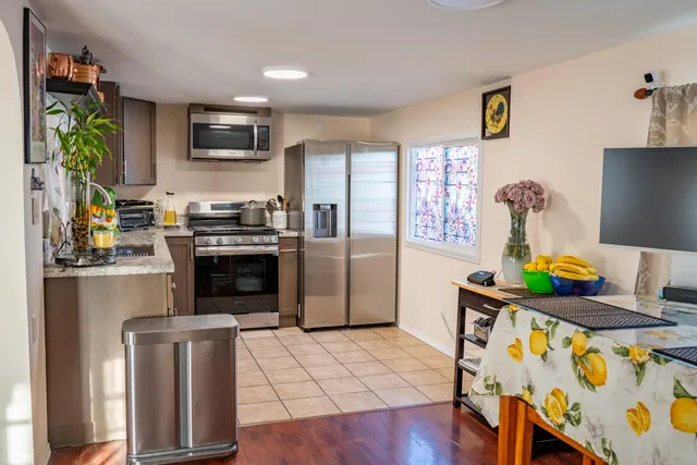 a kitchen with stainless steel appliances a stove a refrigerator a sink a stove white cabinets and wooden floor