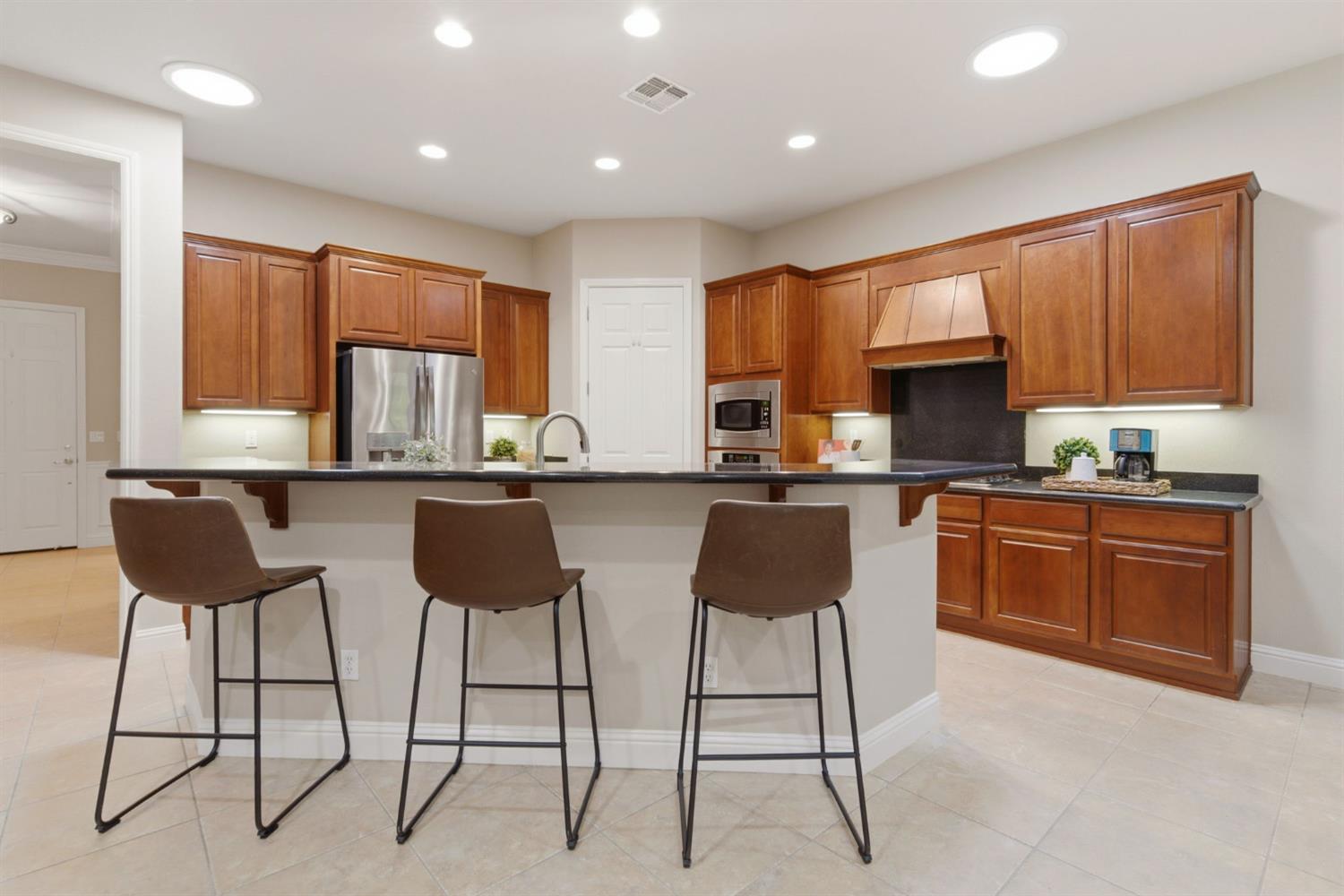 2499 Appleleaf Lane Manteca, CA 95336 - Photo 28 of 55 a kitchen with stainless steel appliances granite countertop a stove a sink a microwave a dining table and chairs