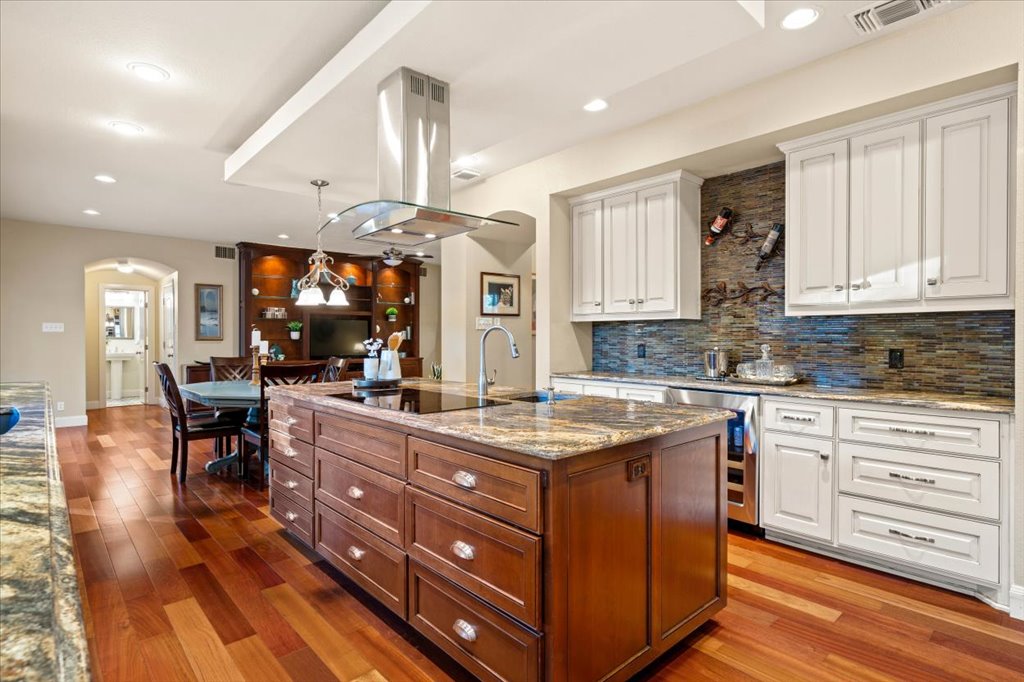 3803 Frodo Cove Austin, TX 78739 - Photo 12 of 40 a kitchen with stainless steel appliances kitchen island granite countertop a stove a sink dishwasher and white cabinets with wooden floor