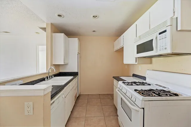 a kitchen with stainless steel appliances granite countertop a sink stove oven and white cabinets