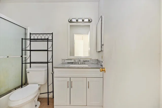 a bathroom with a granite countertop sink toilet and mirror