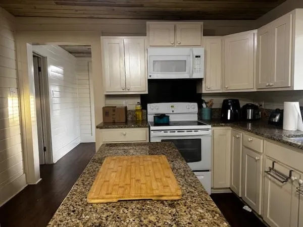 a kitchen with granite countertop a sink a stove and cabinets