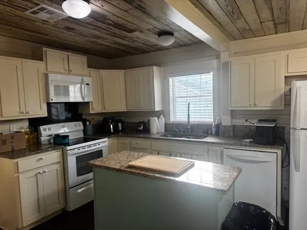 a kitchen with granite countertop a sink a stove and a refrigerator