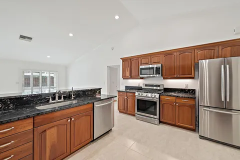 a large kitchen with stainless steel appliances granite countertop a stove a sink dishwasher a refrigerator and a oven