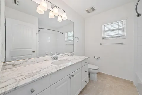 a bathroom with a granite countertop sink mirror and toilet