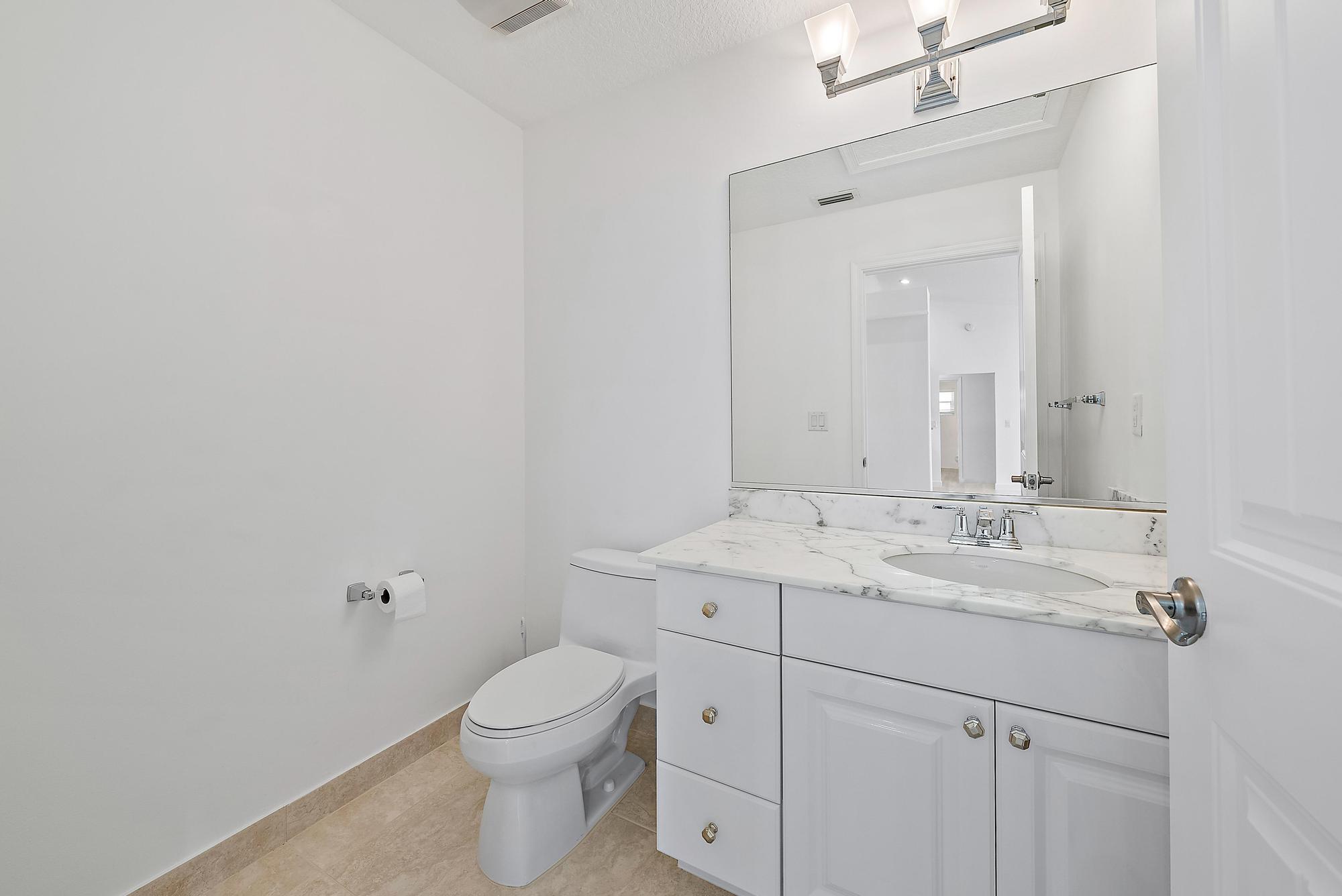 12 Bentwood Road Palm Beach Gardens, FL 33418 - Photo 23 of 40 a bathroom with a granite countertop sink a toilet and a mirror