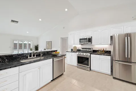 a kitchen with stainless steel appliances granite countertop a stove a sink a refrigerator a microwave a sink and white cabinets