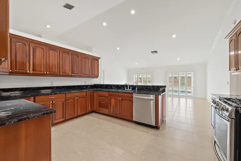a kitchen with stainless steel appliances granite countertop a stove a sink dishwasher and a refrigerator with wooden cabinets