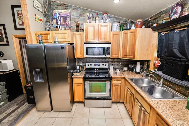 a kitchen with stainless steel appliances granite countertop a refrigerator a stove a sink and a microwave
