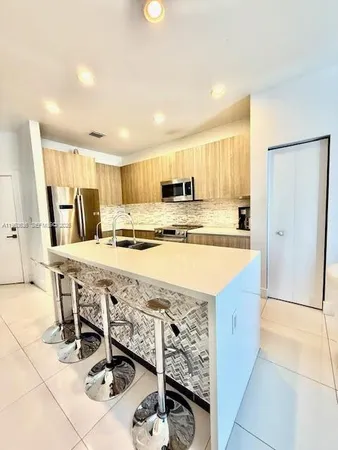 a kitchen with stainless steel appliances granite countertop a sink and a refrigerator
