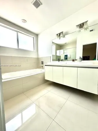 a bathroom with a double vanity sink a mirror and a bathtub