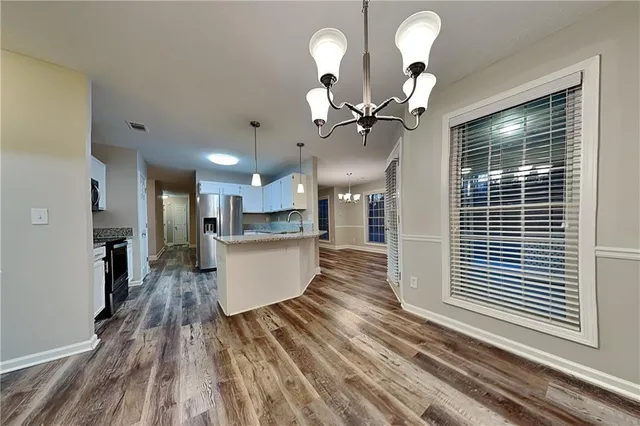 a view of a living room and kitchen with stainless steel appliances wooden floor