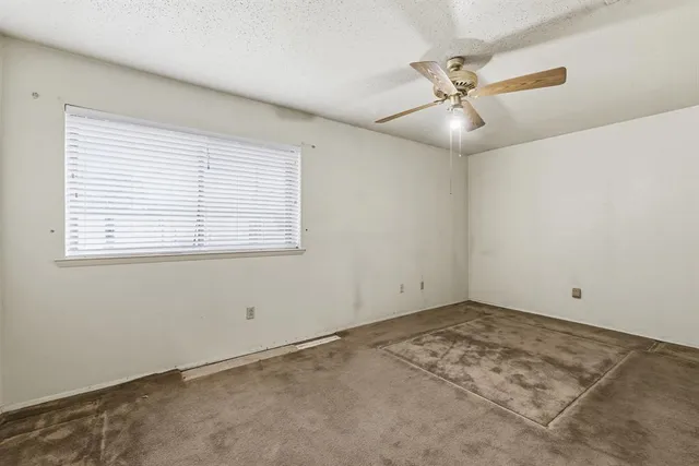 an empty room with a window and a fan