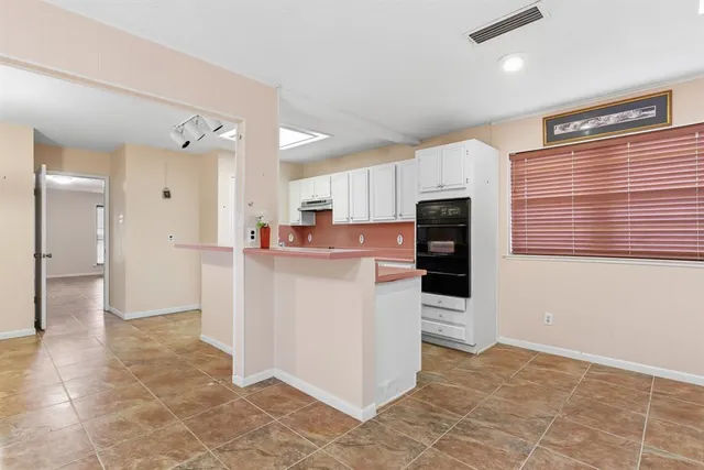 a room view with stainless steel appliances kitchen island granite countertop a refrigerator and a stove top oven
