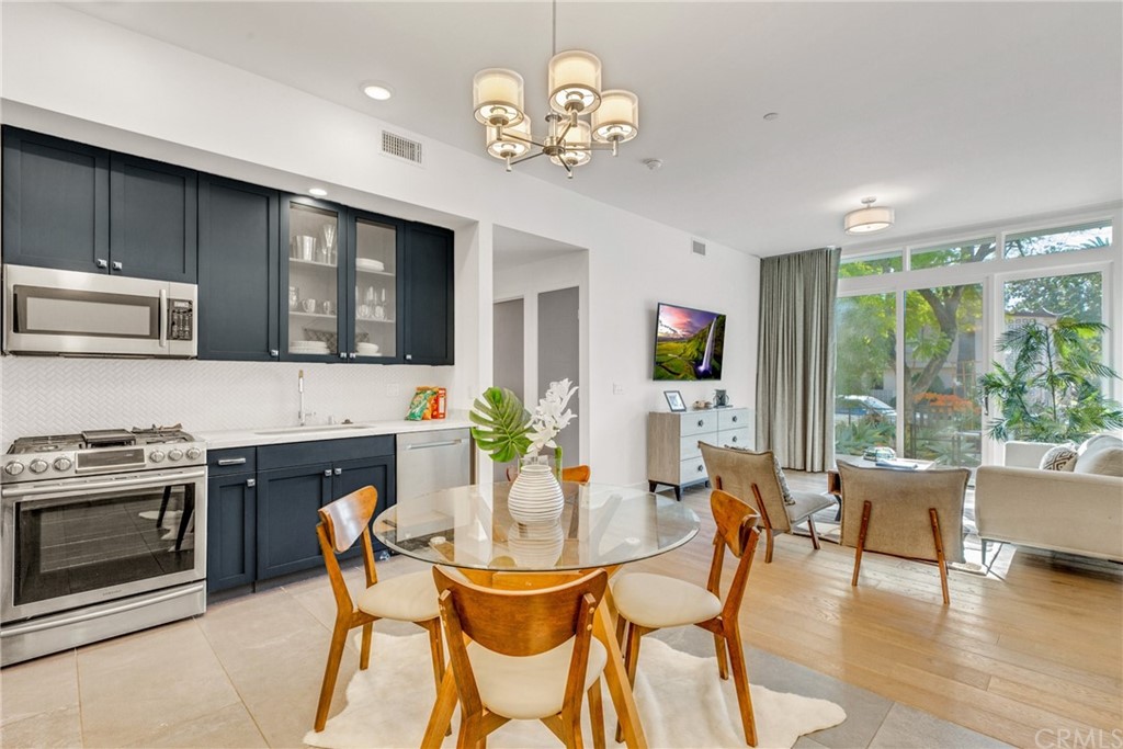 125 Hurlbut Street, Unit 101 Pasadena, CA 91105 - Photo 19 of 53 a dining room with wooden floor a chandelier a glass table and chairs