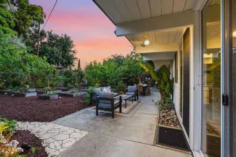 a view of backyard with outdoor seating a patio and plants