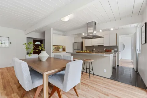 a kitchen with stainless steel appliances a dining table chairs and wooden floor