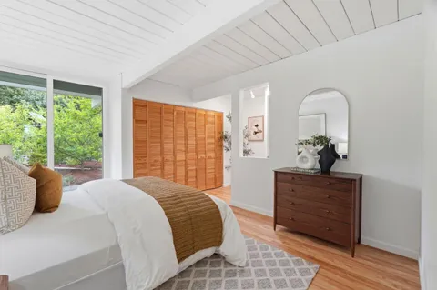 a bedroom with a bed a dresser and with windows