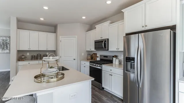 a kitchen with stainless steel appliances a refrigerator stove and white cabinets