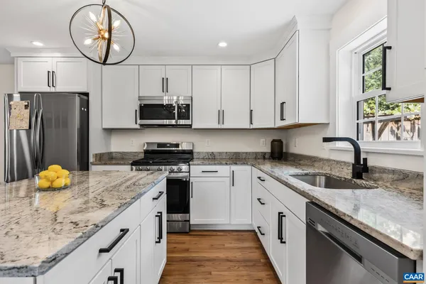 a kitchen with granite countertop a sink a stove and refrigerator