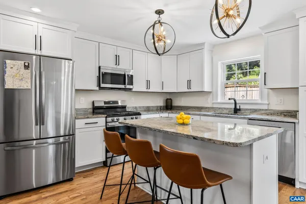 a kitchen with stainless steel appliances granite countertop a stove a refrigerator a microwave oven a sink with a dining table and chairs