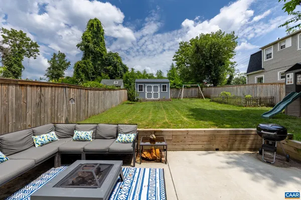 a view of a patio with couches table and chairs with wooden fence and plants