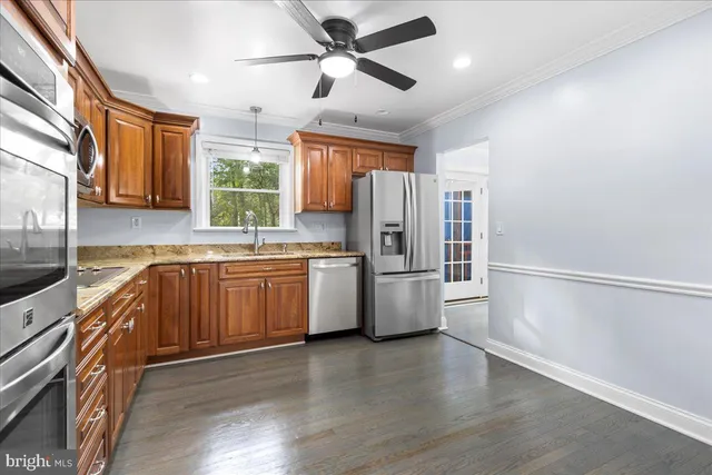 a kitchen with stainless steel appliances a refrigerator a sink and wooden floors