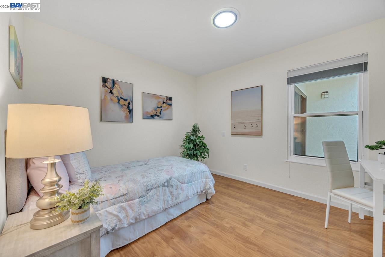4034 Rennellwood Way Pleasanton, CA 94566 - Photo 27 of 42 a bedroom with a bed potted plant on dresser and a wooden floor