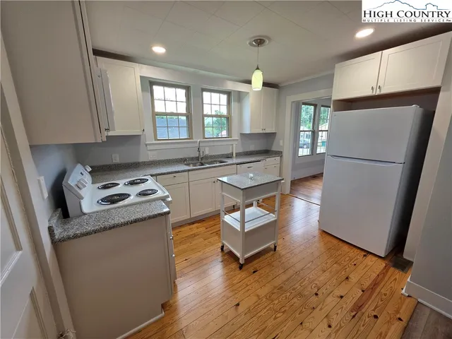 a kitchen with sink a refrigerator and wooden floor