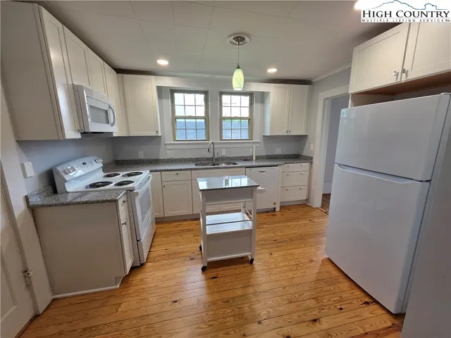 a kitchen with stainless steel appliances granite countertop a refrigerator a sink dishwasher a stove with wooden floors and cabinets