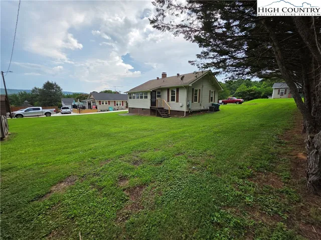 a view of a house with a big yard plants and large trees