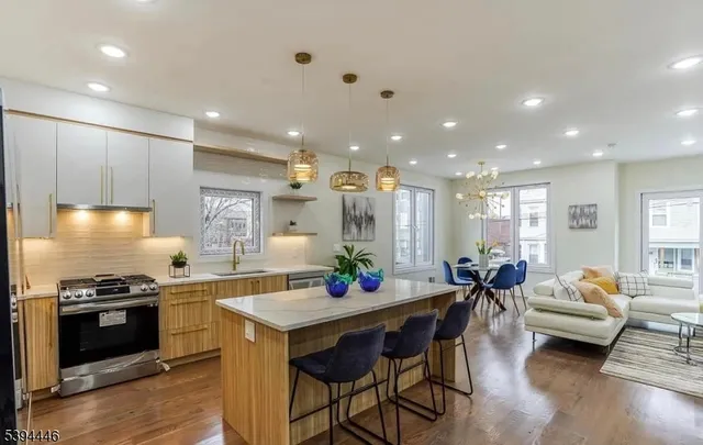 a kitchen with stainless steel appliances kitchen island granite countertop a stove a sink and a dining table with wooden floor