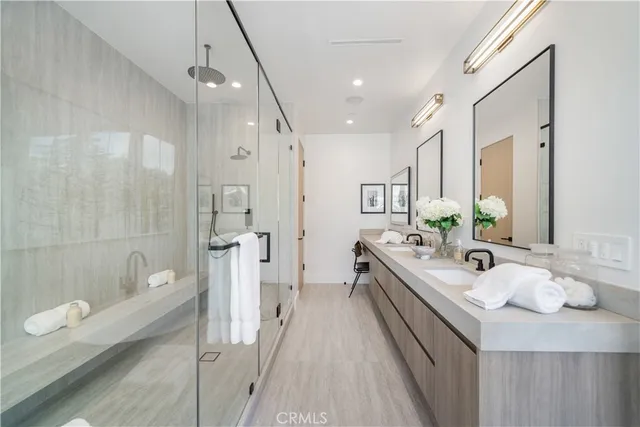 a bathroom with a double vanity sink a toilet a mirror and shower