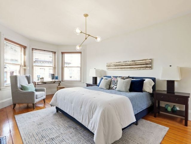 a bedroom with a bed a couch and large windows