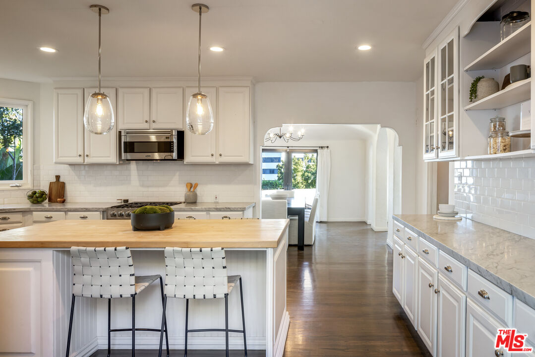 8420 Cresthill Road Los Angeles, CA 90069 - Photo 9 of 30 a kitchen with stainless steel appliances granite countertop a table chairs sink refrigerator and microwave