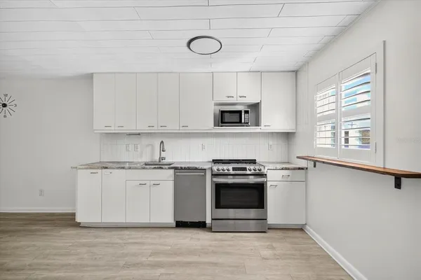 a kitchen with stainless steel appliances granite countertop a stove a sink and a microwave