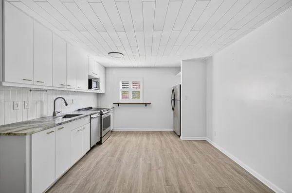 a kitchen with granite countertop a sink cabinets and wooden floor