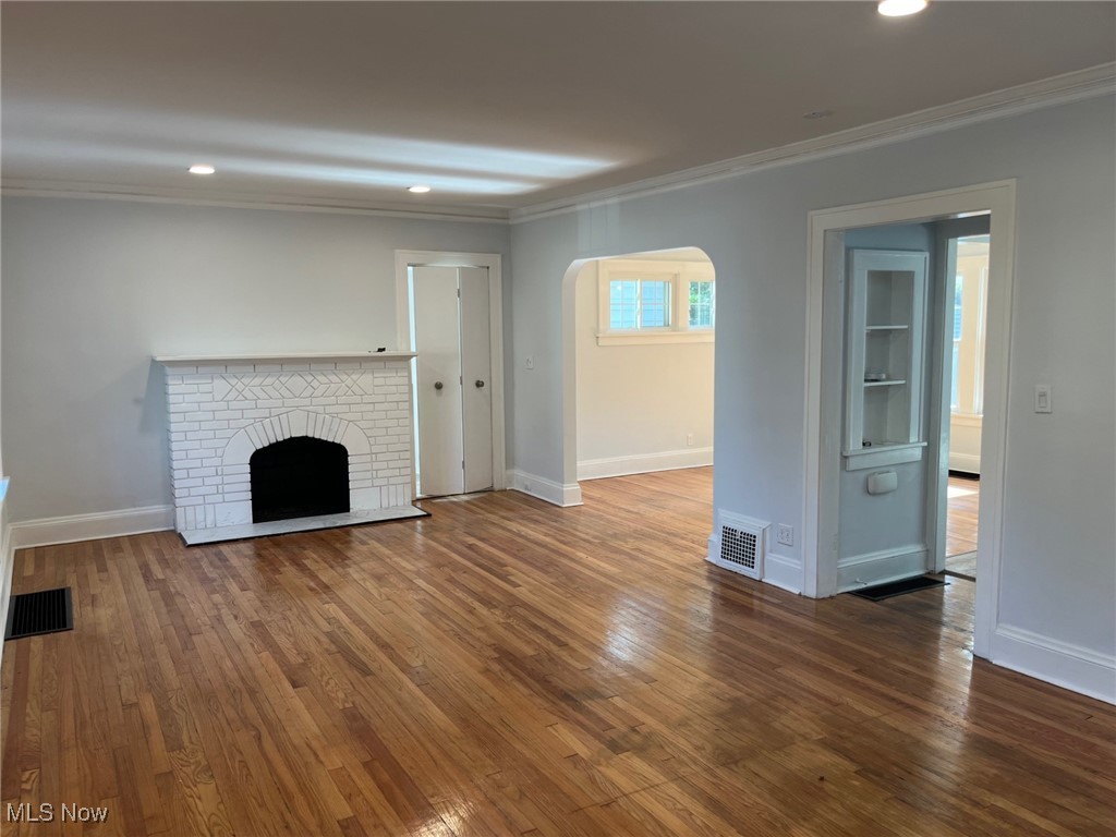 1148 Sylvania Road Cleveland Heights, OH 44121 - Photo 3 of 30 Unfurnished living room featuring arched walkways, recessed lighting, a fireplace, dark wood-style floors, and crown molding