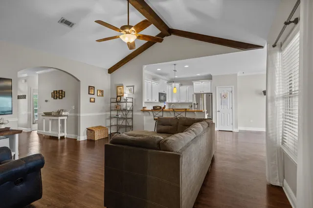 a living room with couches and kitchen view with wooden floor